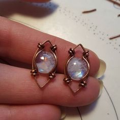 a pair of earrings that are in someone's hand with the ring on it