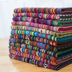 a stack of multicolored cloths sitting on top of a wooden table