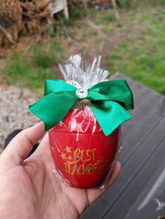 a hand holding an ornament with a green bow on it's ribbon