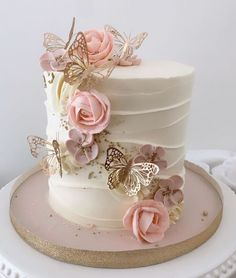 a white cake with pink flowers and butterflies on it's side, sitting on a plate