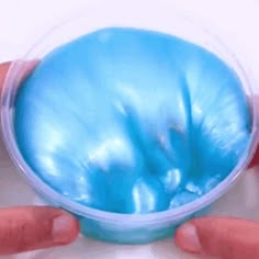 two hands holding a blue object in a plastic container