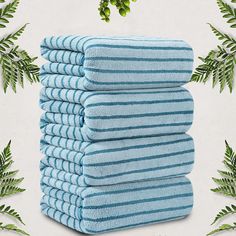 a stack of blue towels sitting on top of a white table next to green leaves