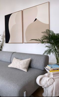 a living room with two paintings on the wall and a couch in front of it