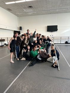 a group of people posing for a photo in an empty room with their arms up