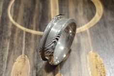 a silver ring sitting on top of a wooden floor