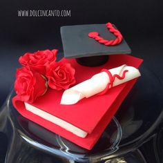 a graduation cake with red roses and a book