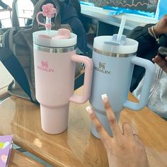 two coffee mugs sitting on top of a table next to each other, one with a straw in it