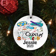 a personalized ornament hanging from a christmas tree with scissors and sewing supplies