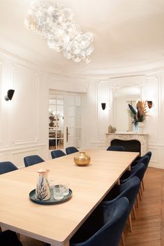 a dining room table with blue chairs and a chandelier hanging from the ceiling