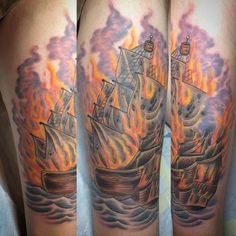 a man's arm with a ship on fire and flames