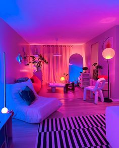 a living room filled with lots of furniture and colorful lighting on the walls, along with a black and white striped rug