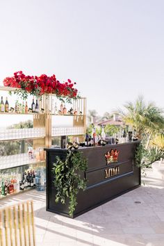 the bar is decorated with red flowers and wine bottles on it's shelfs