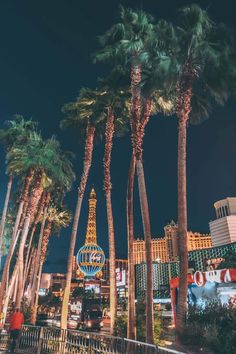 the las vegas strip at night with palm trees and neon signs in the foreground