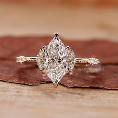 a diamond ring sitting on top of a wooden table next to a piece of leaf