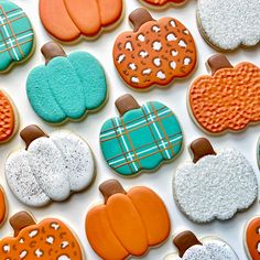 many decorated pumpkins and cookies on a white table top with blue, orange, and brown icing