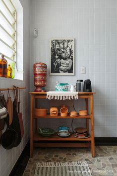 a kitchen counter with pots and pans sitting on it's shelf next to a window