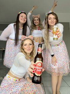 four women dressed in costumes holding up beer bottles