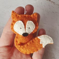 a hand holding a small felt fox ornament