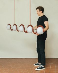 a man is standing in front of three hanging lights that look like balls and chains