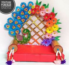 the colorful paper flowers and peacocks are arranged on top of a red box with gold trim