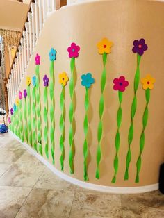 flowers are painted on the side of a wall with green grass and straws attached to it