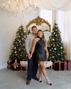 a man and woman standing in front of a christmas tree