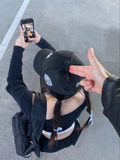 a person taking a photo with their cell phone while wearing a hat and black jacket