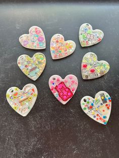 six heart shaped magnets sitting on top of a black table next to each other