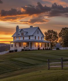 a large white house sitting on top of a lush green field under a cloudy sky