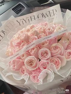 a bouquet of pink roses sitting on top of a car dashboard