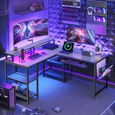 a computer desk with two monitors on top of it in front of a purple wall