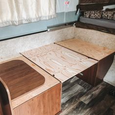 a wooden table sitting on top of a hard wood floor next to a white curtain