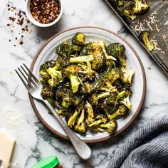 broccoli and other vegetables on a plate next to a baking sheet, spoons and seasonings