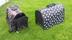 two black and white dog carrier bags sitting in the grass next to each other on top of green grass