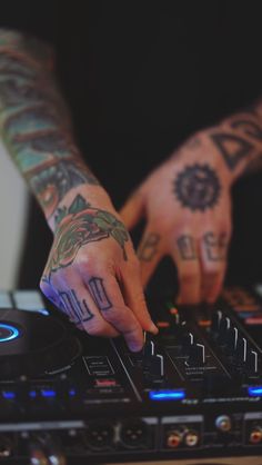 a person with tattoos on their arm and hands, playing music on a dj's turntable