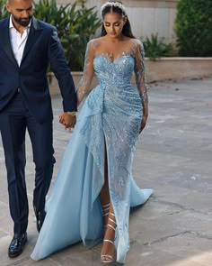 a man and woman dressed in formal wear walking down the street holding hands with each other