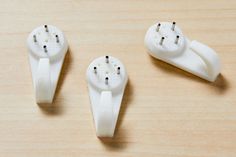 three white electrical plugs sitting on top of a wooden table