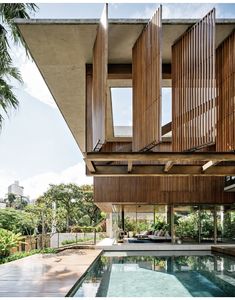 an outdoor swimming pool in front of a house with wooden slats on the roof