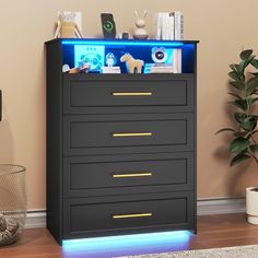 a black chest of drawers with blue lights on the top and bottom drawer, next to a potted plant