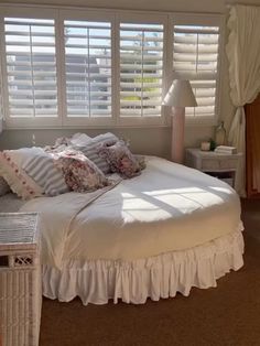 a white bed sitting in a bedroom next to a window with shutters on it