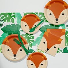 four paper plates with foxes on them and green leafy napkins next to each other