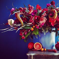 a blue vase filled with lots of flowers and fruit