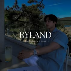 a man sitting at a table next to a glass of water and a sign with the name ryand on it