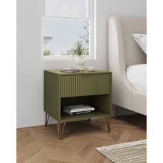 a nightstand with a book on it in front of a window and a white bed