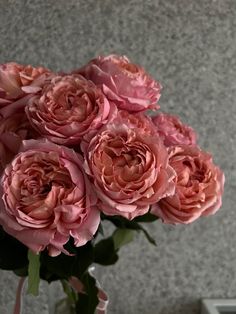 a vase filled with pink flowers sitting on top of a table next to a wall