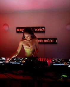 a woman in a bathing suit djing at a turntable with headphones on