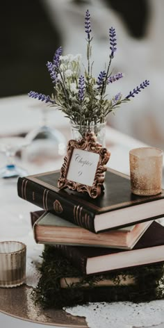 a stack of books sitting on top of a table next to a vase filled with flowers