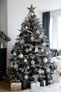 a black and white christmas tree decorated with silver, gold and star ornaments in a living room