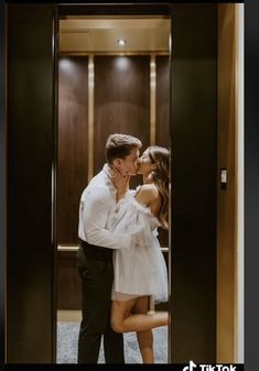 a man and woman kissing in front of a glass door at the entrance to an elevator