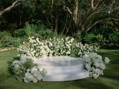 white flowers are growing on the side of a large circular planter in a garden